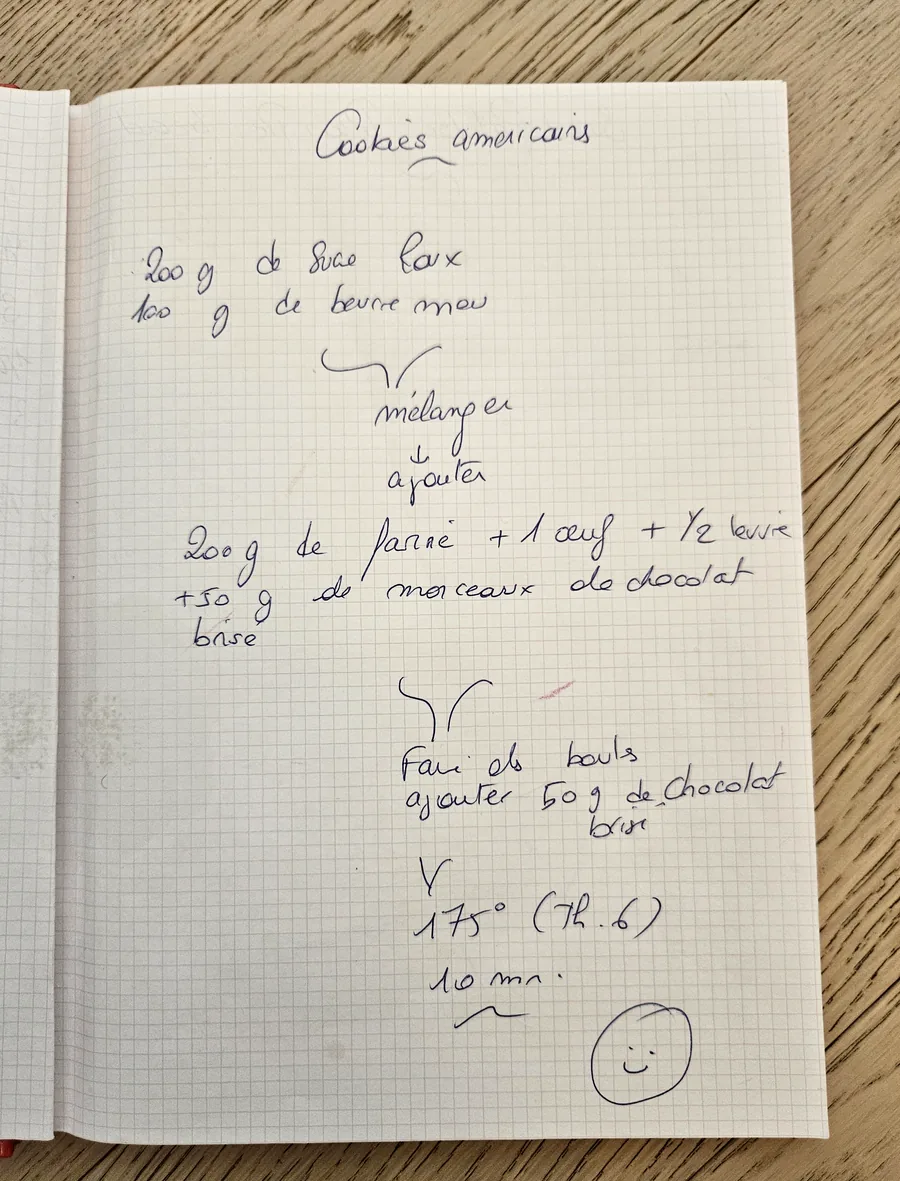 An open notebook on a table, the cookie recipe written by hand
